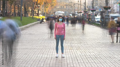 The woman with medical face mask stands in the crowded city. time lapse