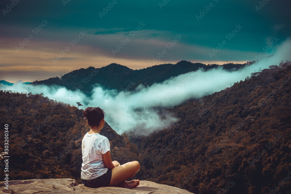 Beautiful Srilankan girl look at distance mountain while sitting on a rock mountain