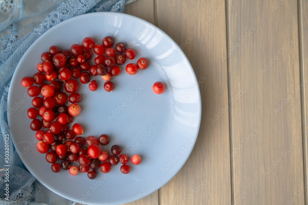 Red cranberries on blue plate top view on wooden background. Red cranberries on blue plate top view on wooden background.
