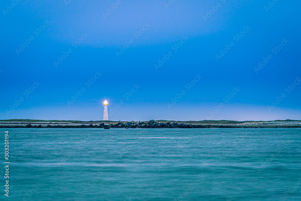 Lighthouse seascape smooths out the ocean surface while the light shines with long exposure.