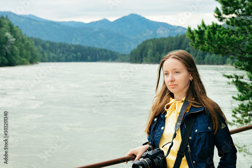 Young girl with camera at Altai mountains and Katun River in Siberia in Russia © Roman Babakin
