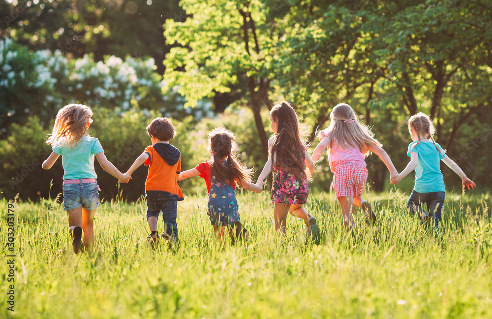 Obraz premium Large group of kids, friends boys and girls running in the park on sunny summer day in casual clothes .