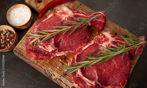 Fresh beef steak with herbs and salt on a stone background