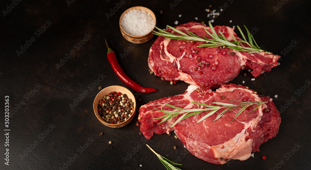 Fresh beef steak with herbs and salt on a stone background