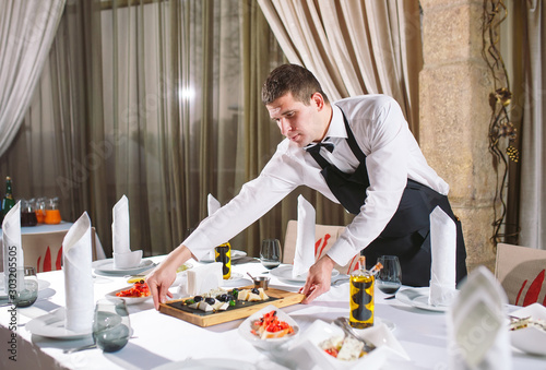Waiter serving table in the restaurant preparing to receive guests.