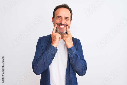 Fototapeta Naklejka Na Ścianę i Meble -  Middle age handsome man wearing blue denim shirt standing over isolated white background Smiling with open mouth, fingers pointing and forcing cheerful smile