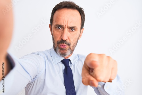 Middle age businessman wearing tie make selfie standing over isolated white background pointing with finger to the camera and to you, hand sign, positive and confident gesture from the front