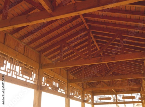 Photo of the interior part of the roof of a large wooden pavilion with decorative elements on perimeter. © nadeene_ko