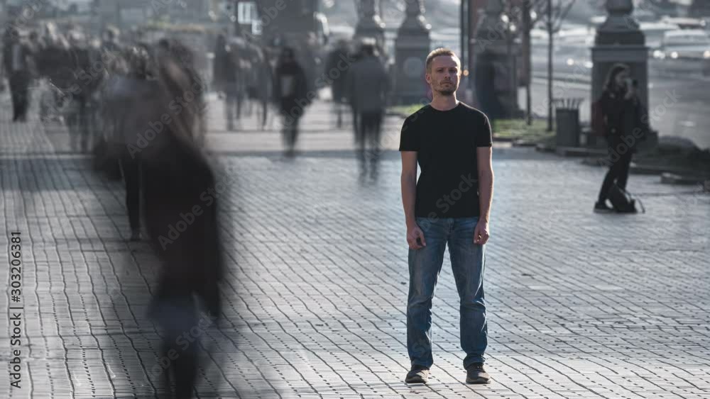 The man stands in the middle of urban crowdy stream. time lapse