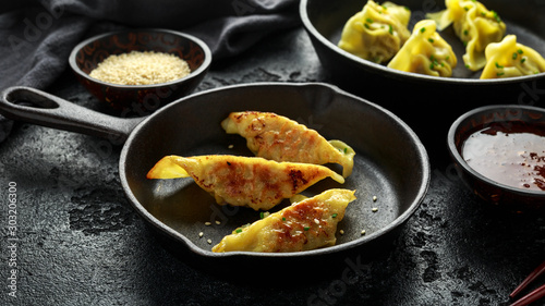 Steamed and Fried yaki Gyoza served on cast iron skillet, pan with sweet chilli sauce and sesame seeds