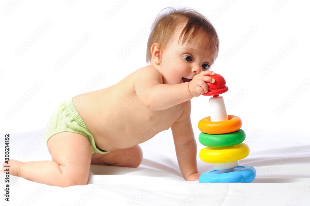 Pretty one year little baby playing with colorful pyramid. Child sits and holds loved toy portrait on light background Pretty one year little baby playing with colorful pyramid. Child sits and holds loved toy portrait on light background