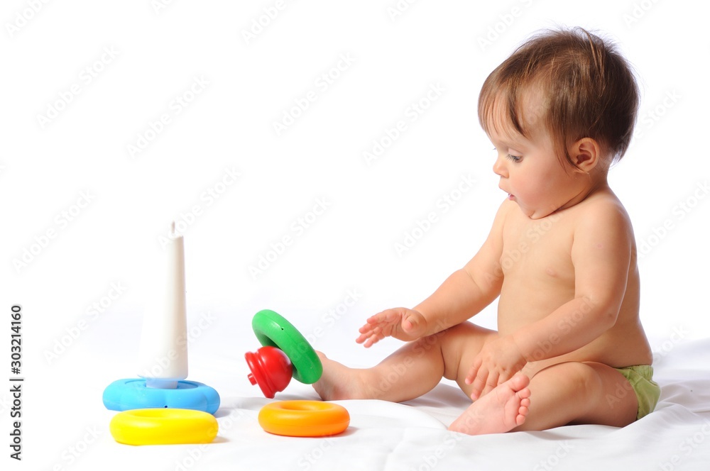 Surprised funny one year baby sitting and playing with loved toy. Leisure and happy childhood. Isolated on white background Surprised funny one year baby sitting and playing with loved toy. Leisure and happy childhood. Isolated on white background