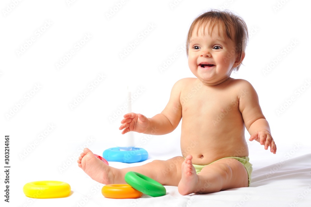 Happy laughing little child sits and plays with loved toy. Baby pyramid. Adorable baby girl portrait on isolated white background Happy laughing little child sits and plays with loved toy. Baby pyramid. Adorable baby girl portrait on isolated white background