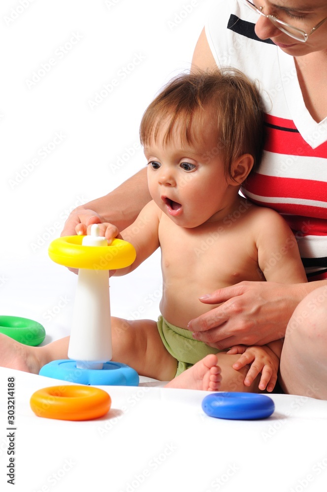 Funny training play of colorful pyramid with loved mother. Little baby sitting and playing toy with parent. Isolated on white background Funny training play of colorful pyramid with loved mother. Little baby sitting and playing toy with parent. Isolated on white background