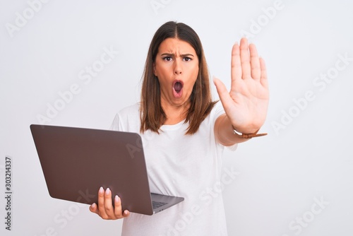 Beautiful young woman working using computer laptop over white background doing stop gesture with hands palms, angry and frustration expression