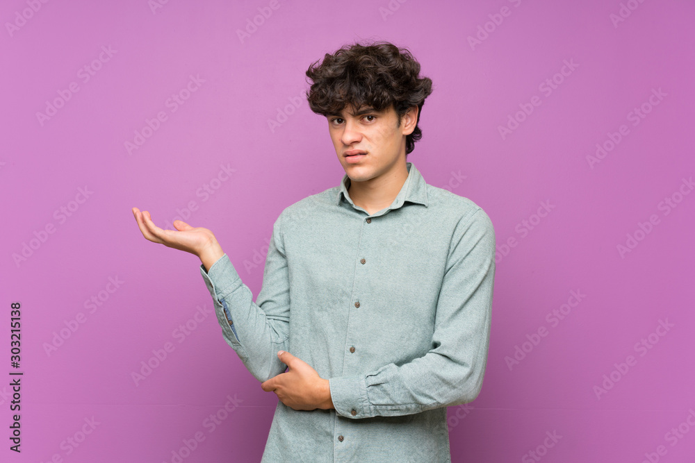 Young man over isolated purple wall unhappy for not understand something Young man over isolated purple wall unhappy for not understand something