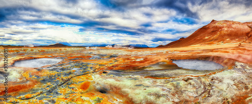 Boiling mudpots in the geothermal area Hverir and cracked ground around