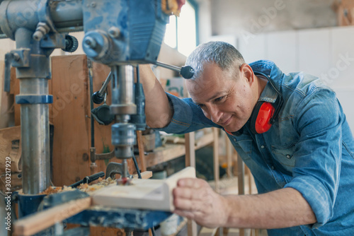 Mature carpenter using drill press in workshop © Dragana Gordic