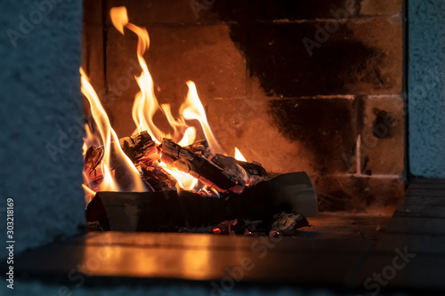 Open fireplace  firewood and fire  giving heat  on a cold winter evening  in a cozy house.