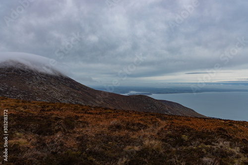 Murlough Nature reserve viewable in the distance as Mountain mist rolls of Slieve Donard, Mourne mountains, County Down, Northern Ireland © stevie