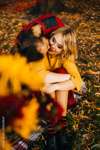 Romantic picnic of young couple in the park. Yellow and red colors. The moment of the kiss