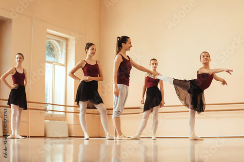 Ballet instructor helping ballerina with posture during dance class.