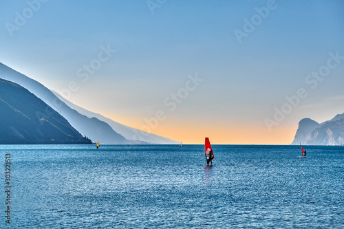 ,Italy - 19 October 2018: Windsurfer Surfing The Wind On Waves In Garda Lake, Recreational Water Sports, Extreme Sport Action. Recreational Sporting Activity. Healthy Active Lifestyle