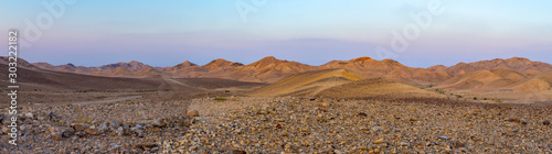 Panoramic view of stone desert land with desertic arid mountains and rocks in the background