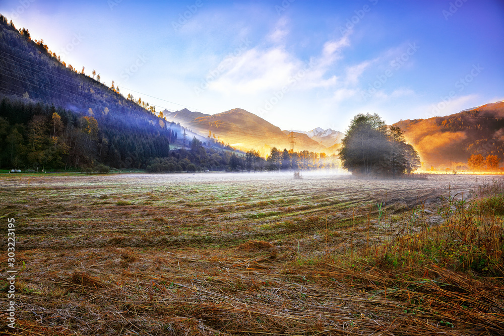 Spectacular autumn view of meadow in morning mist near Sell Am See