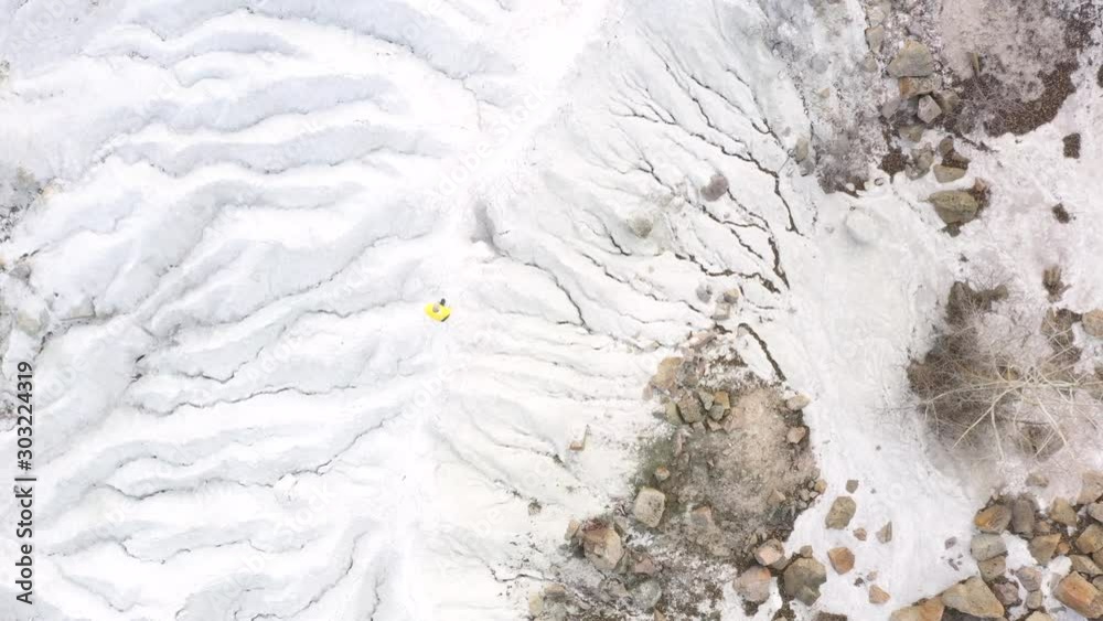 Aerial drone view of old man with gray hair and beard in yellow raincoat walking at the salt canyon. Top view of elderly hike tourist in salt canyon Aerial drone view of old man with gray hair and beard in yellow raincoat walking at the salt canyon. Top view of elderly hike tourist in salt canyon