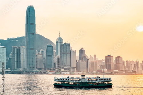 Star ferry at Victoria Harbor and Hong Kong skyline at sundown. View from Kowloon on HK Island.