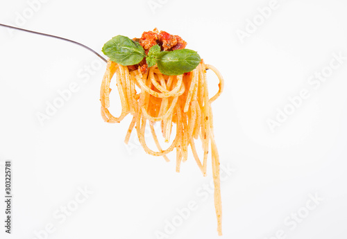 Spaghetti bolognese on a fork on a white background decorated with fresh mint leaves