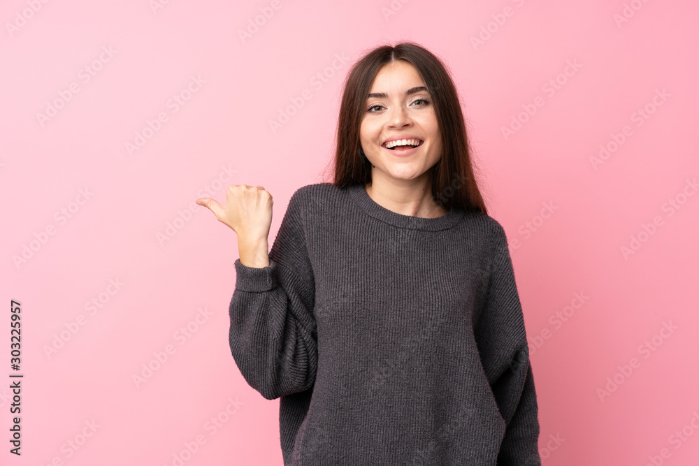 Young woman over isolated pink background pointing to the side to present a product Young woman over isolated pink background pointing to the side to present a product