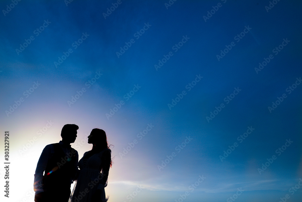 Silhouette of a man and woman on the beach at sunset.
