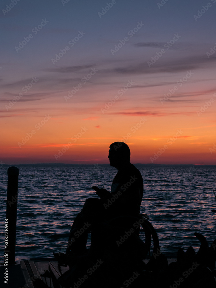 A silhouette of a handicapped young limitless man in a wheelchair enjoying the sunset over Lake Apopka near Orlando,Florida.