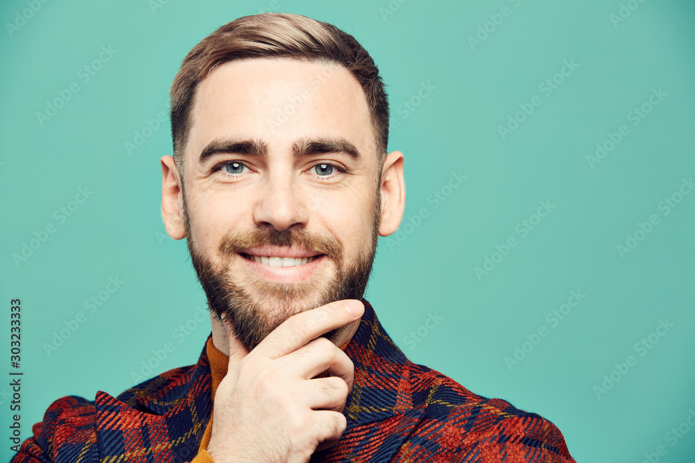 Head and shoulders portrait of smiling bearded man looking at camera while posing against mint green background, copy space Head and shoulders portrait of smiling bearded man looking at camera while posing against mint green background, copy space