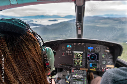 Woman is in the helicopter in Alaska. They are flying over the mountains and glacier. This is a sightseeing excursion photo