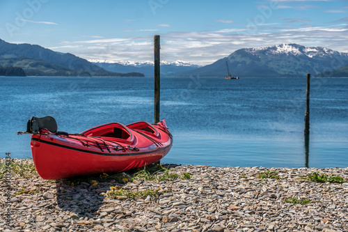 Red kayak is on the beach. Kayaking excursion in Alaska. Expedition on the sea.