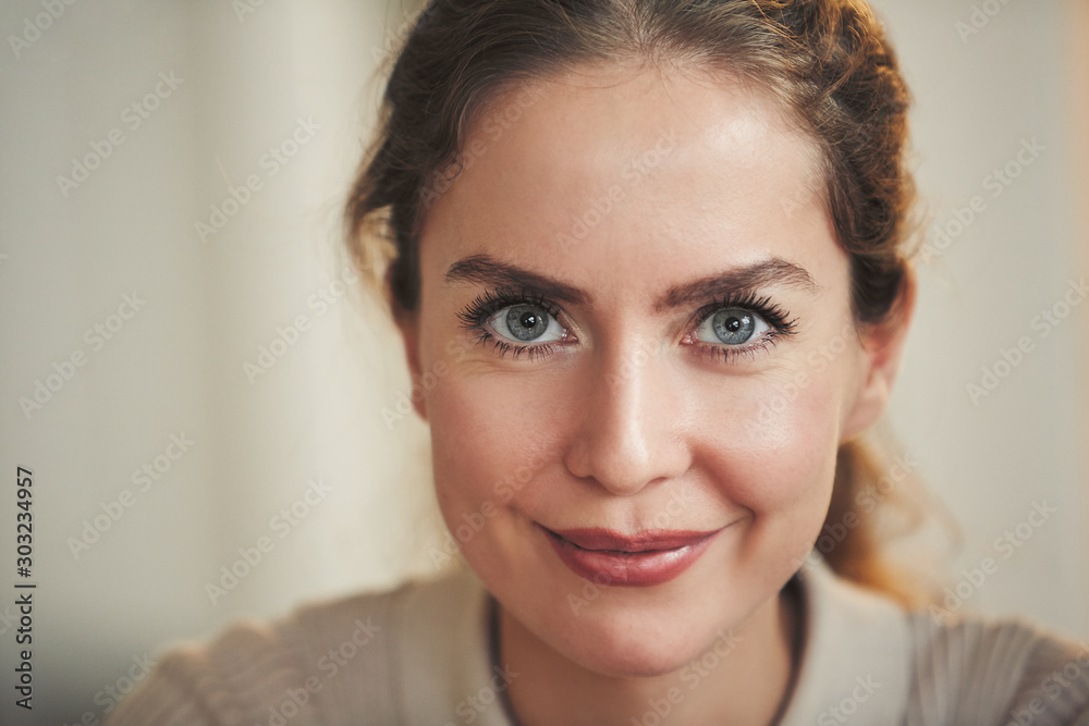 Close up portrait of beautiful adult woman smiling at camera while posing in home interior, copy space Close up portrait of beautiful adult woman smiling at camera while posing in home interior, copy space