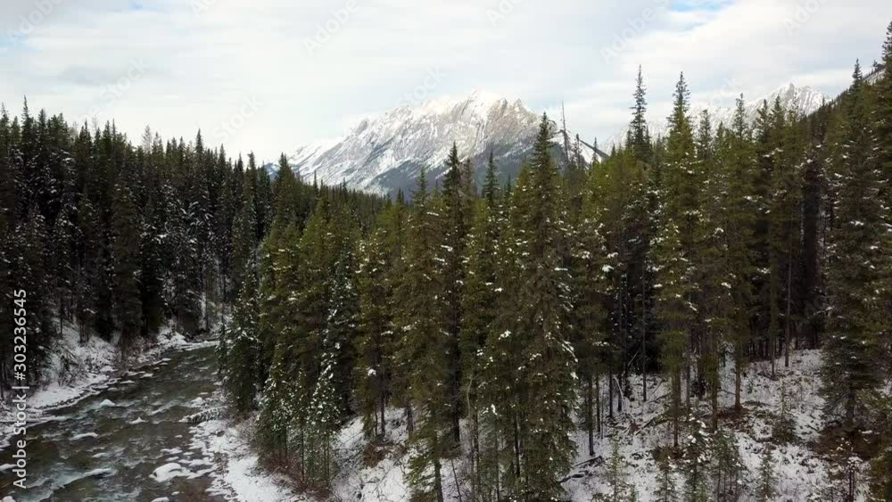 Drone flying over wilderness river revealing amazing Canadian winter landscape with mountains at the end of the valley. Drone flying over wilderness river revealing amazing Canadian winter landscape with mountains at the end of the valley.