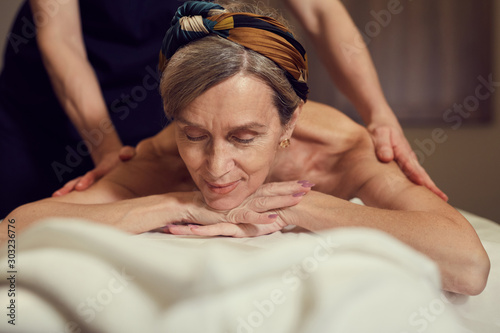 Foto Portrait of elegant senior woman enjoying massage at luxury SPA center, copy spa