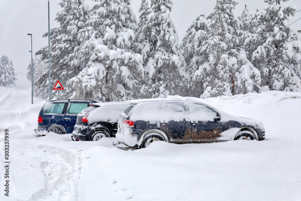 Cars in the parking lot covered in snow during a snowstorm. Image