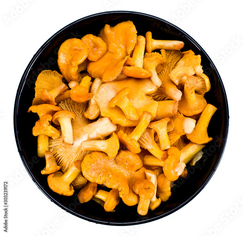 Chanterelles mushrooms in a black bowl isolated on a white background. Top view.