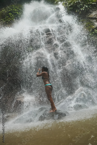 Woman under waterfall  on the bottom of rocks and river.