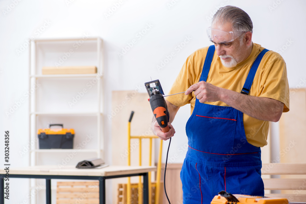 Old male carpenter working in workshop Old male carpenter working in workshop