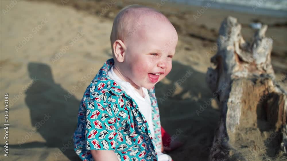 Adorable caucasian little boy is crawling on sandy beach, smiling and laughing Adorable caucasian little boy is crawling on sandy beach, smiling and laughing