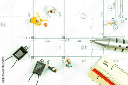Miniature people surveyor technician is measuring the distance to build a house.