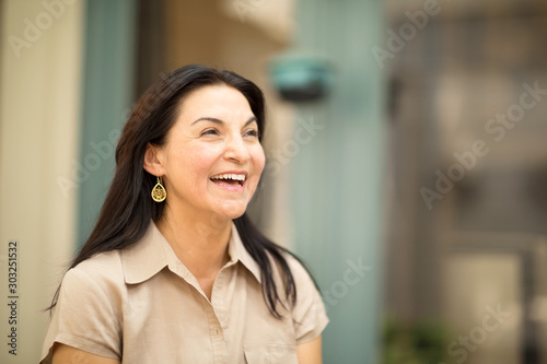 Happy Hispanic woman smiling and standing outside.