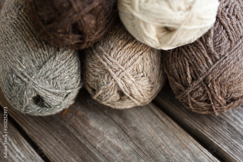 Yarn skeins for handmade. Beige, brown, gray and white balls of yarn. Wooden background, natural wool knitting background