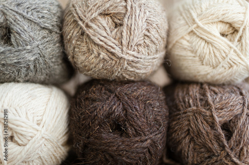 Yarn skeins for handmade. Beige, brown, gray and white balls of yarn. Wooden background, natural wool knitting background